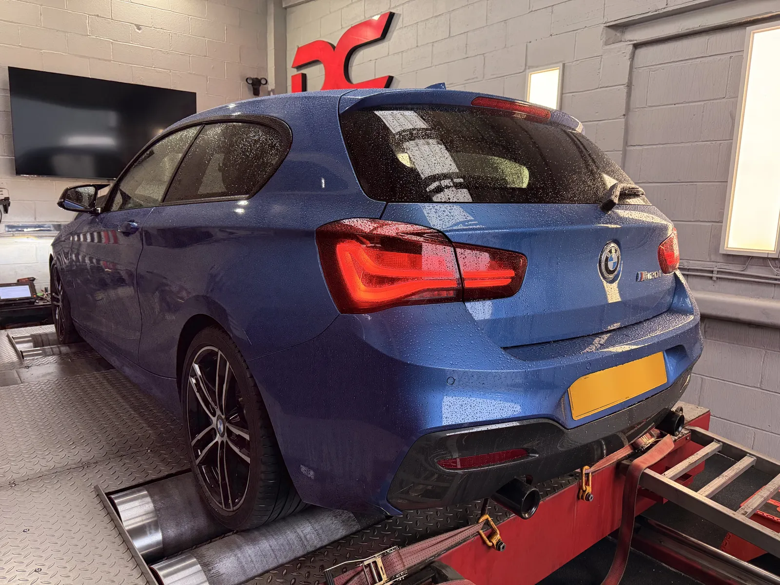 BMW 120i rear three-quarter on the dyno under the DC sign