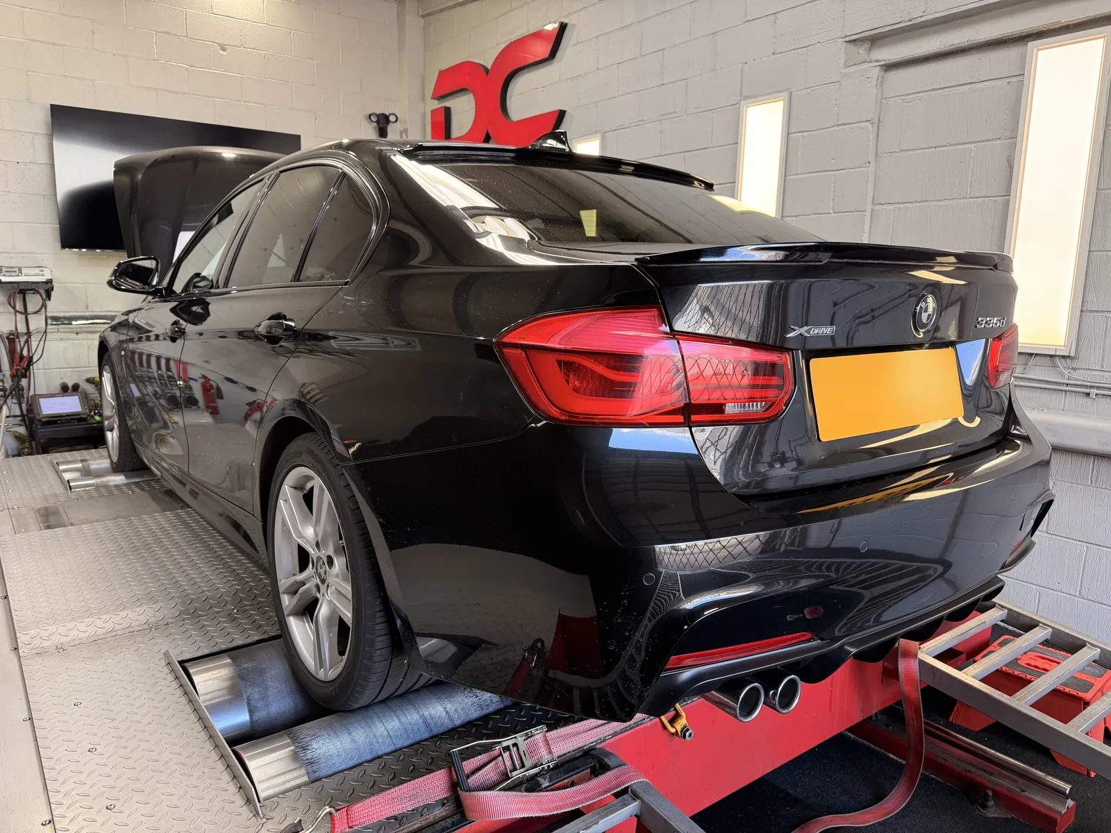BMW 335d xDrive rear three-quarter on the dyno under the DC sign