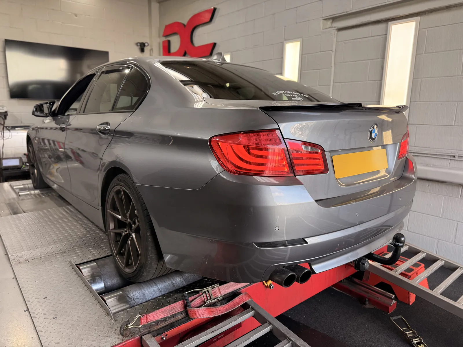 BMW 530d rear three-quarter on the dyno under the DC sign