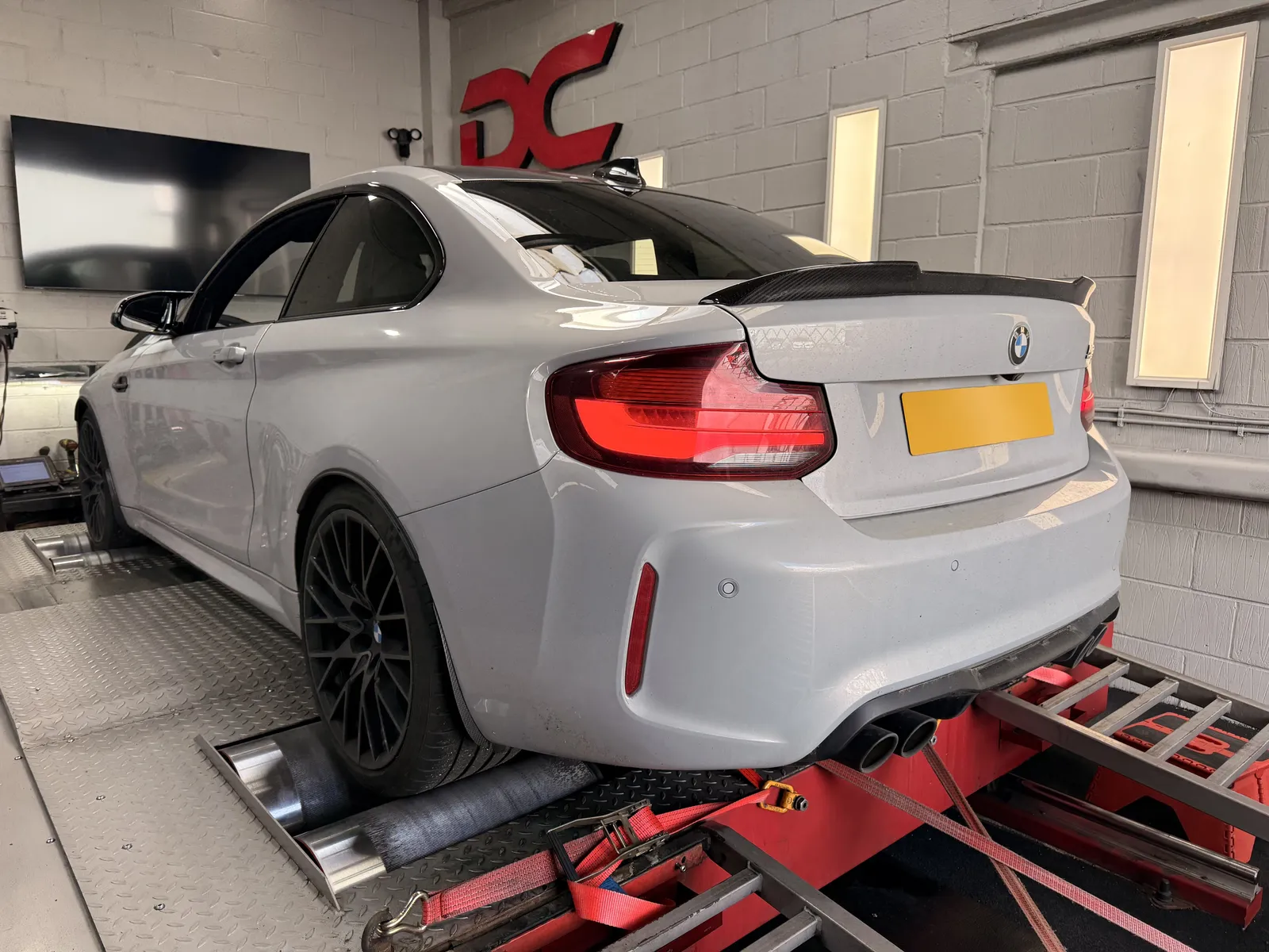 BMW M2 Competition rear three-quarter on the dyno under the DC sign