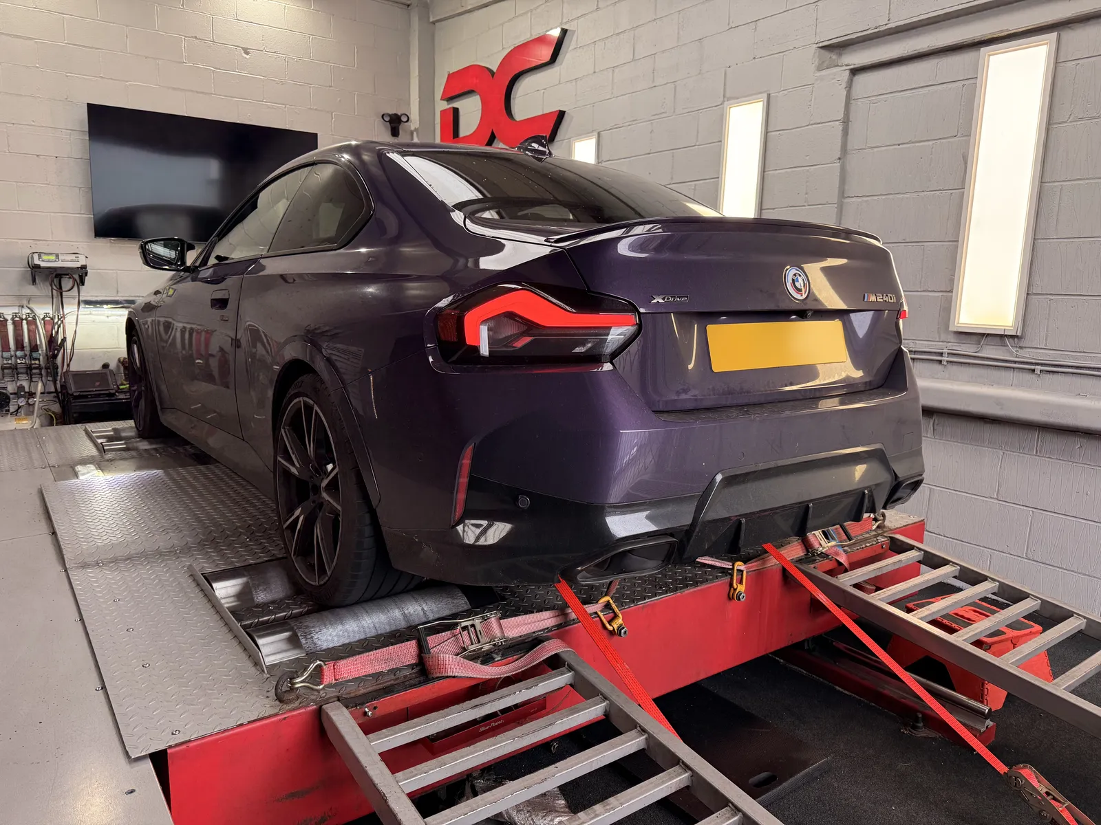 BMW M240i xDrive rear three-quarter on the dyno under the DC sign