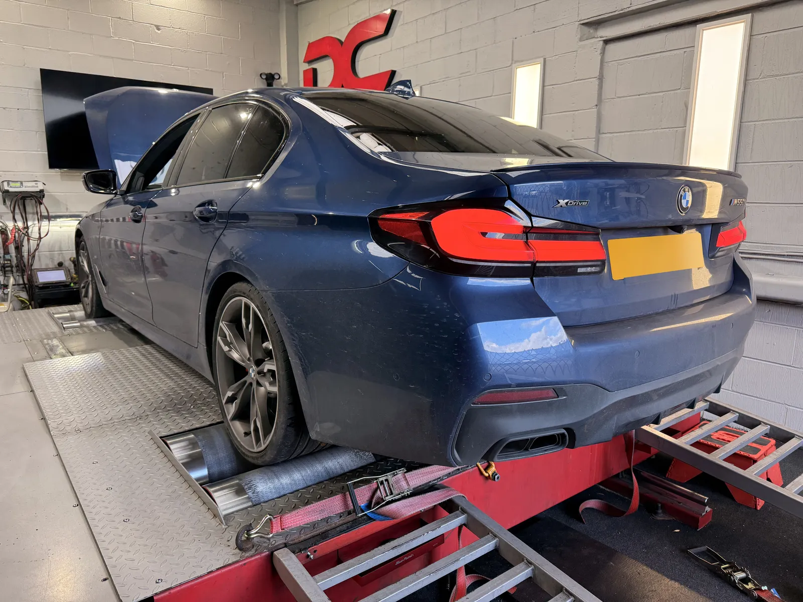 BMW M550i xDrive rear three-quarter on the dyno under the DC sign